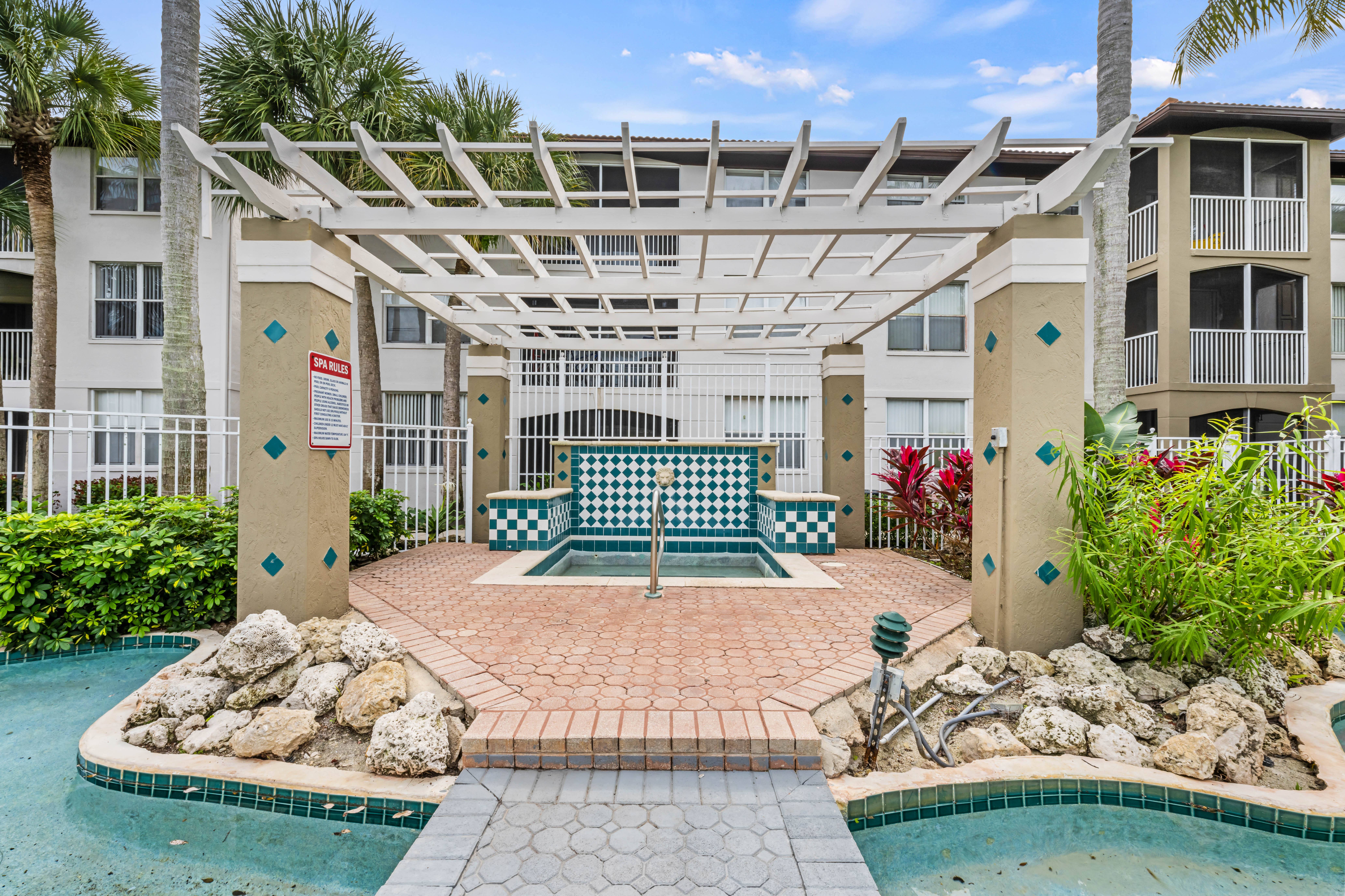 A pool area with a pergola and a bench.